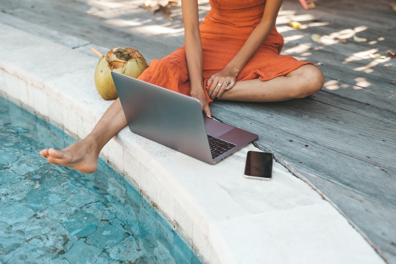 Woman on laptop by pool
